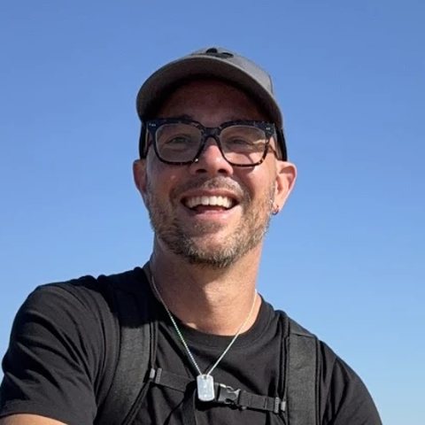 Patrick Miller, smiling on a sand dune above the Pacific